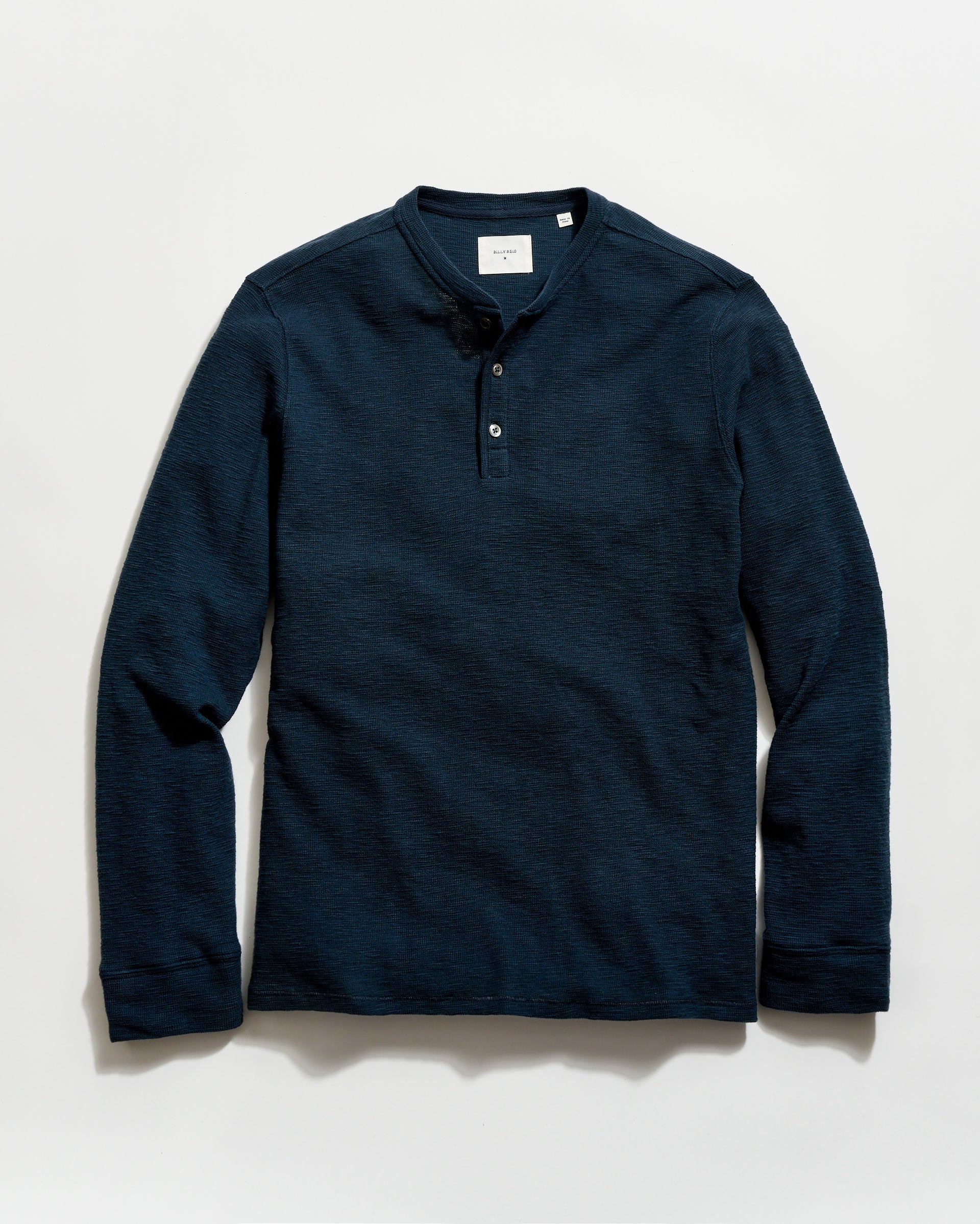 Navy long-sleeve henley shirt on a light gray background