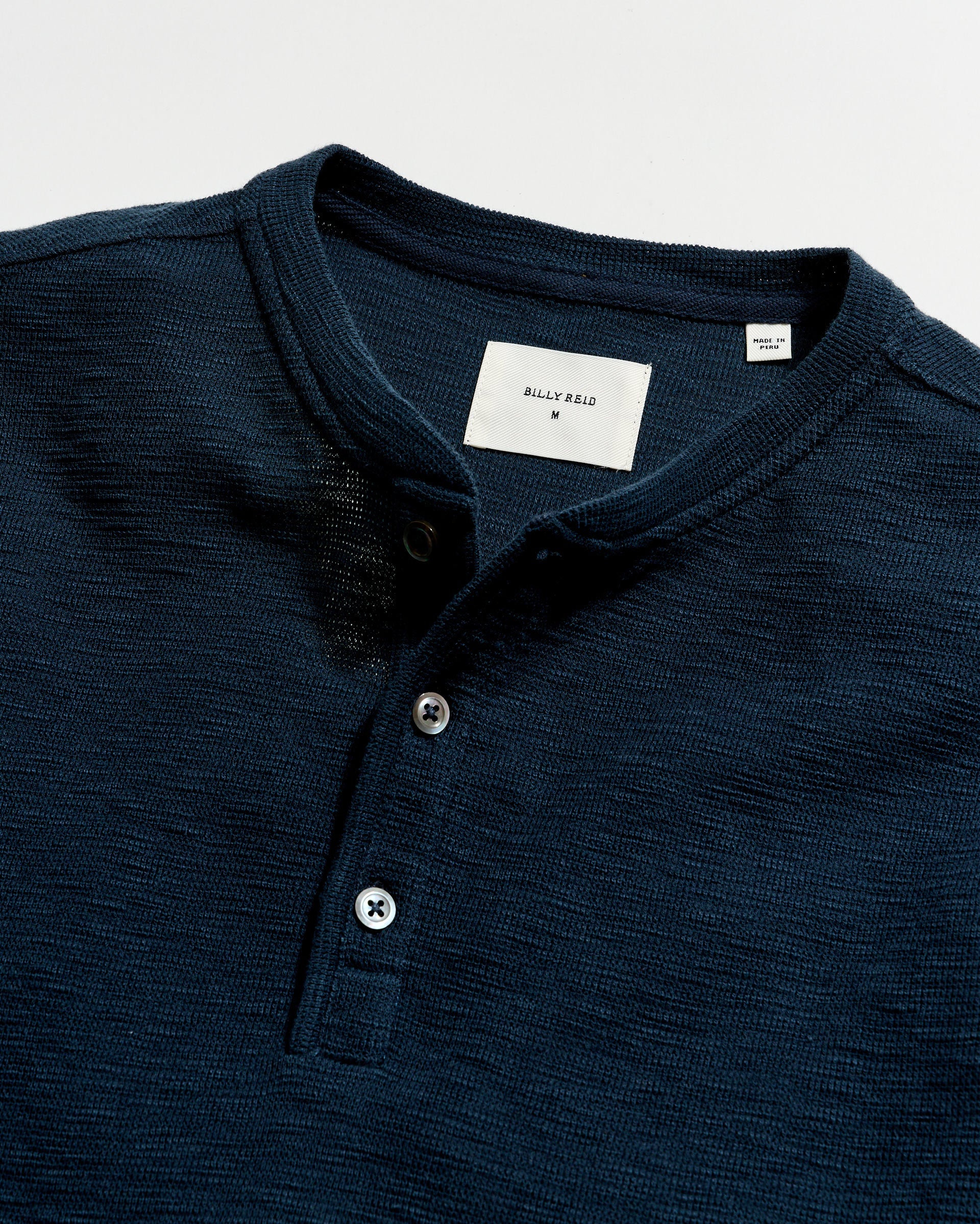 Navy blue polo shirt with brand label on a light gray background