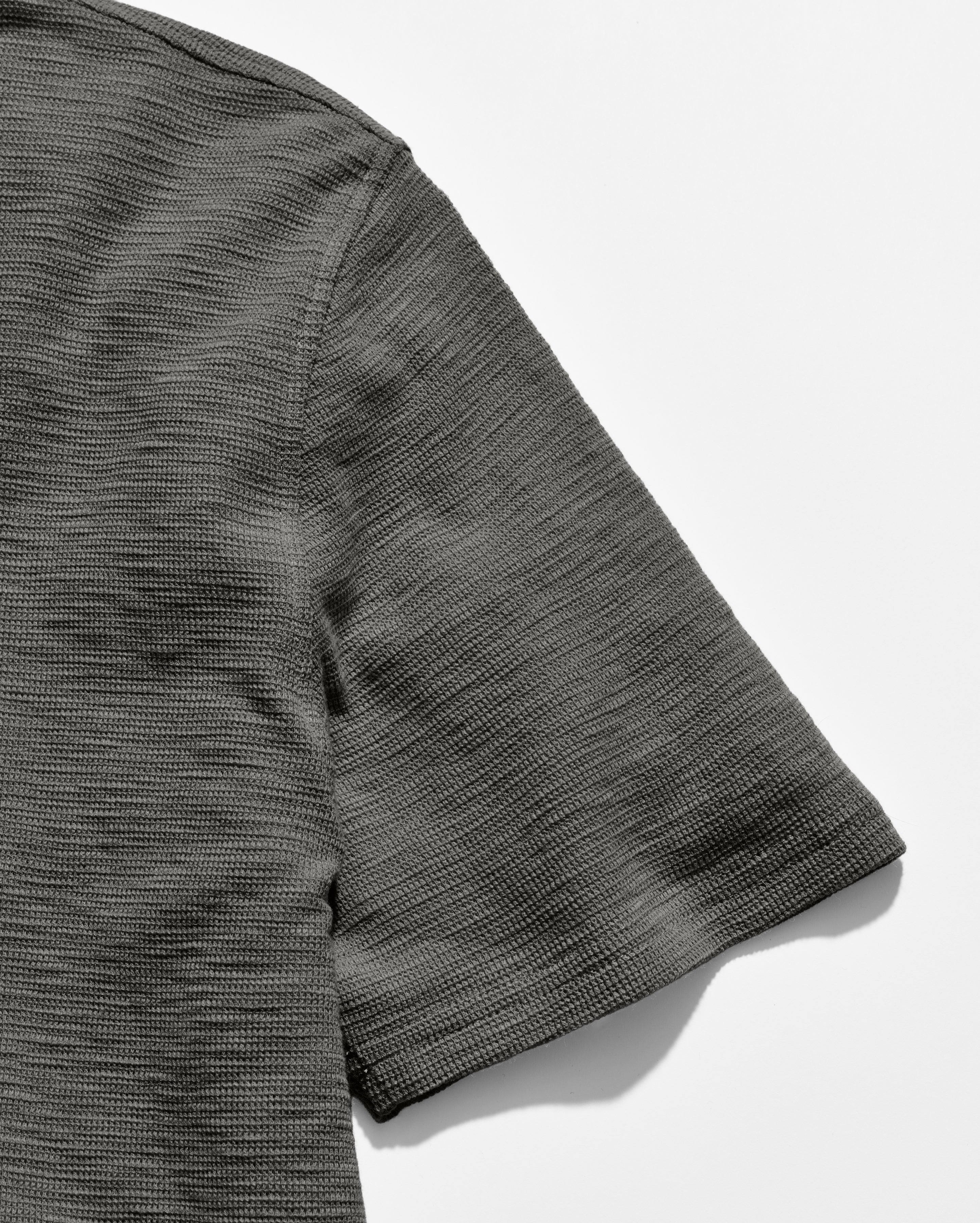 Close-up of a textured gray shirt sleeve on a white background