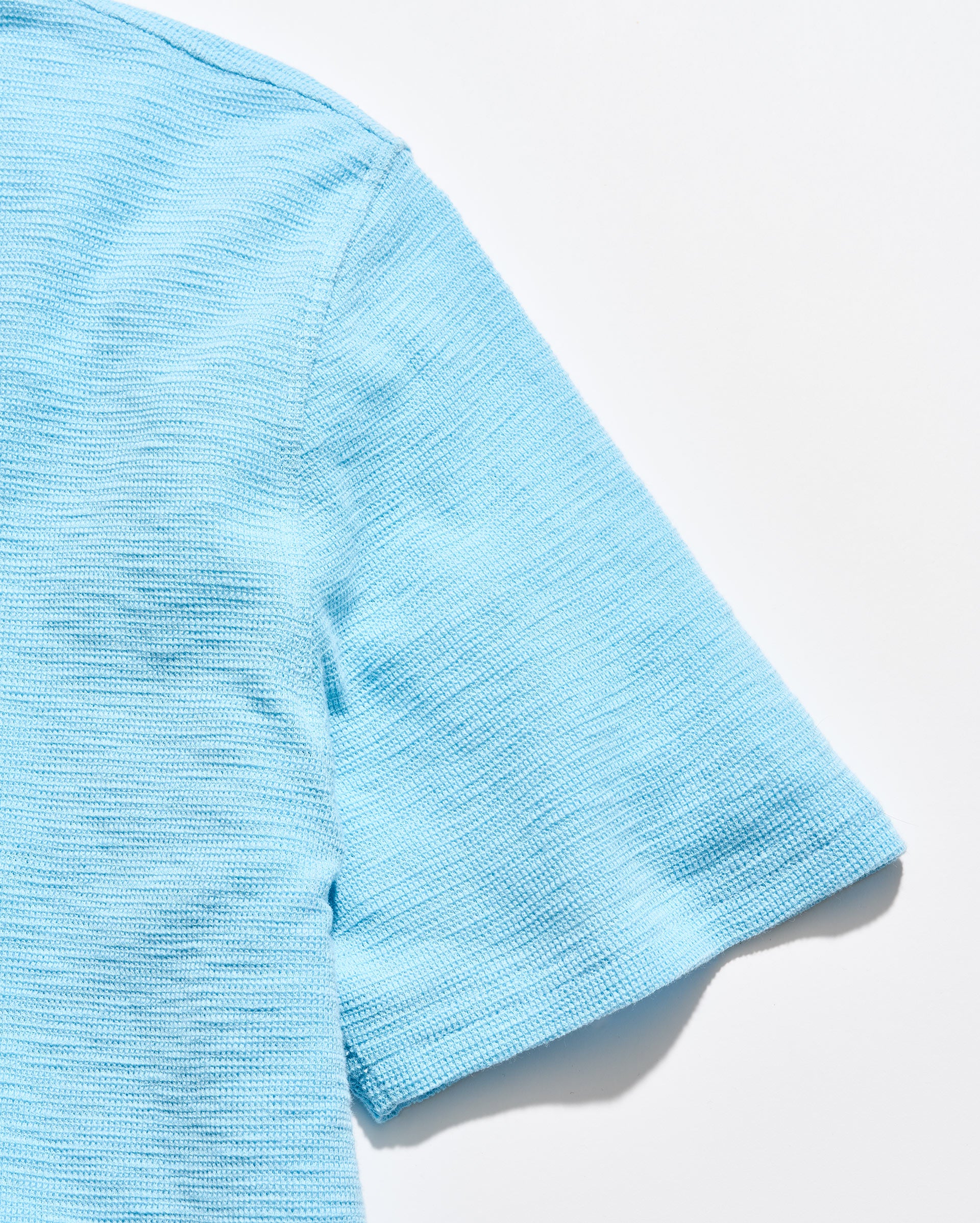 Close-up of a light blue textured fabric on a white background