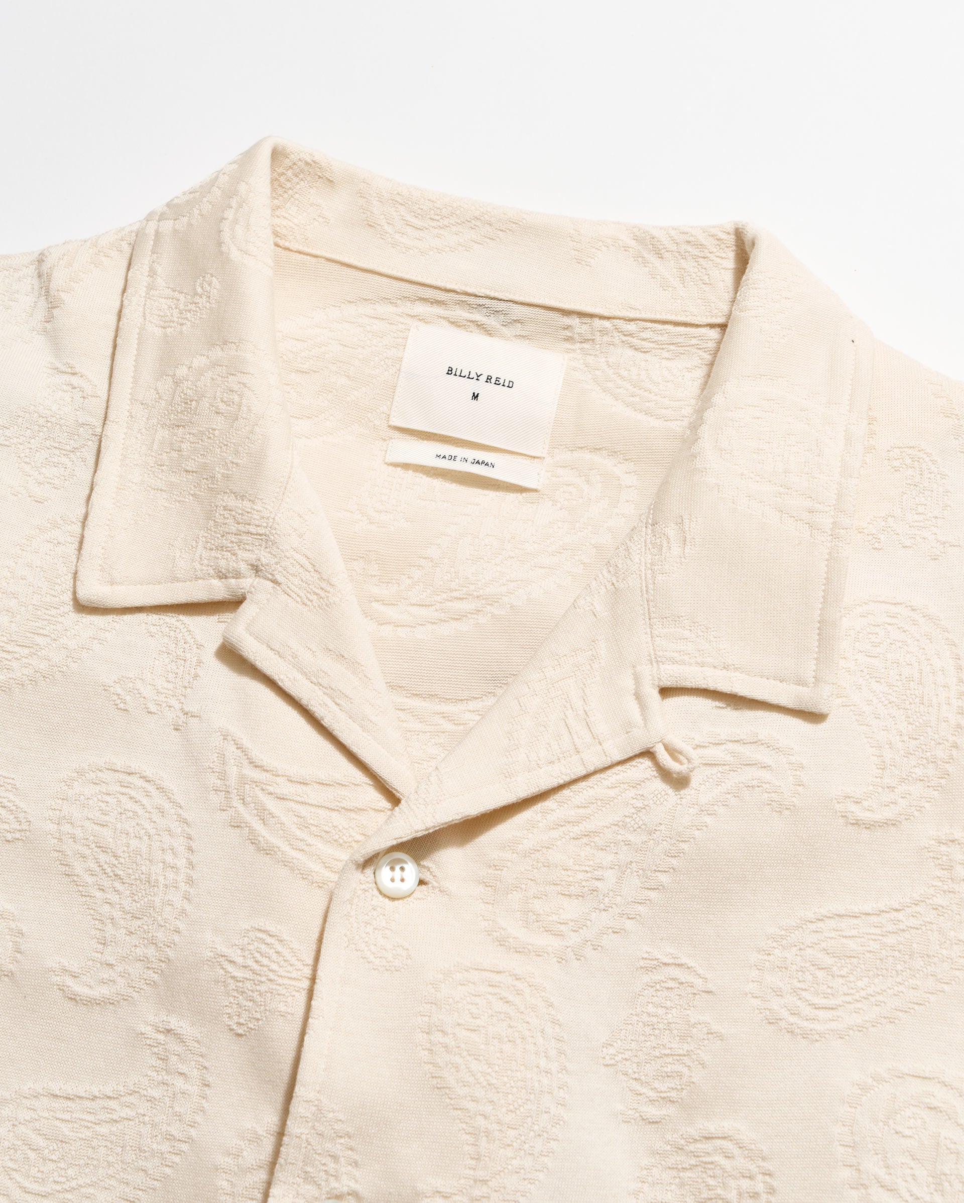 Beige textured shirt with a brand label on a white background