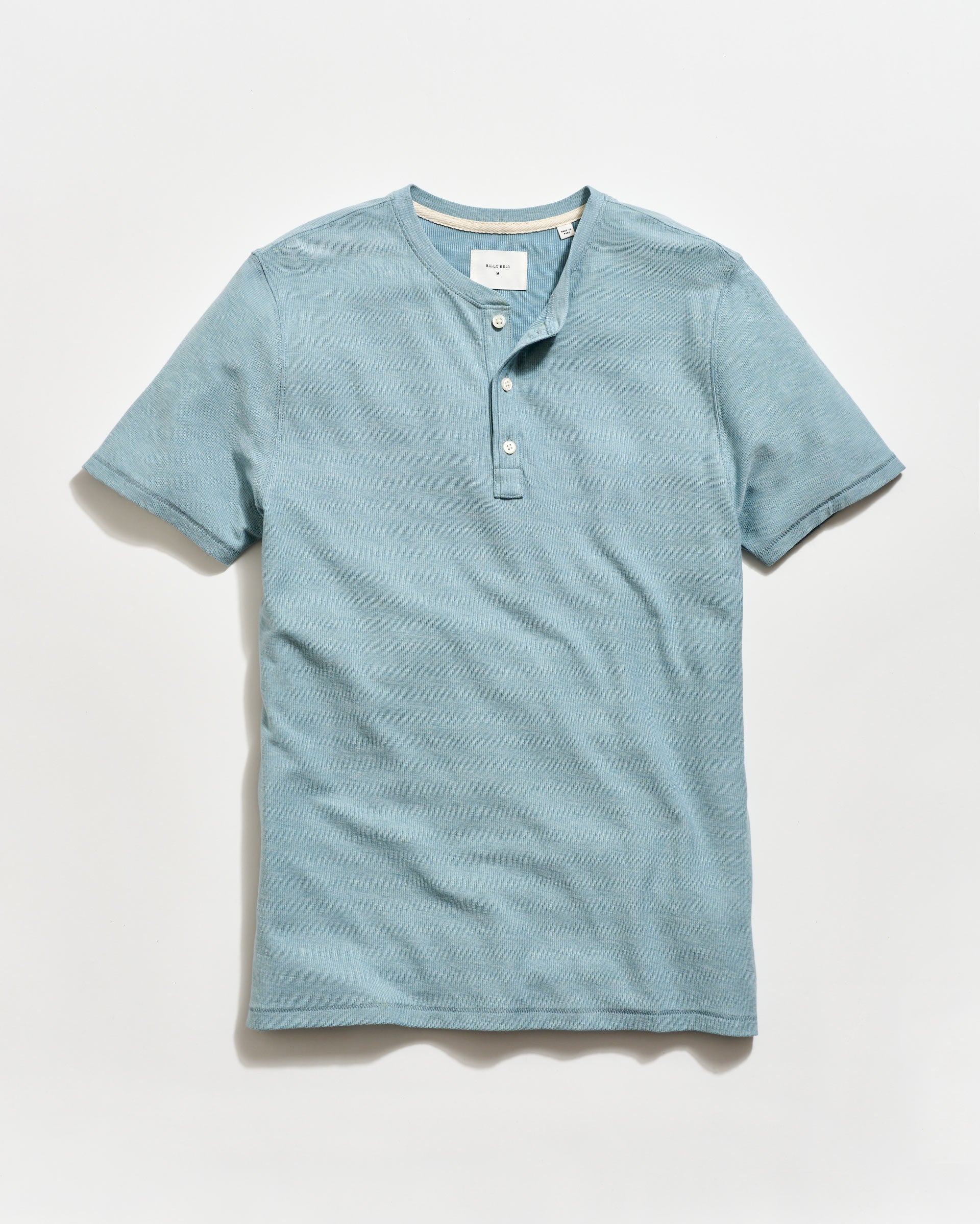 Blue henley shirt on a light gray background
