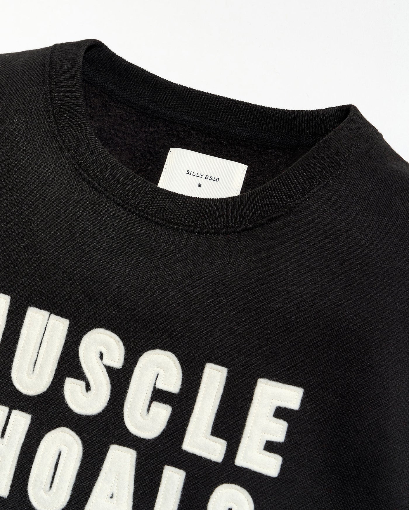 Black t-shirt with 'MUSCLE SHOALS' text and a visible brand label on a white background