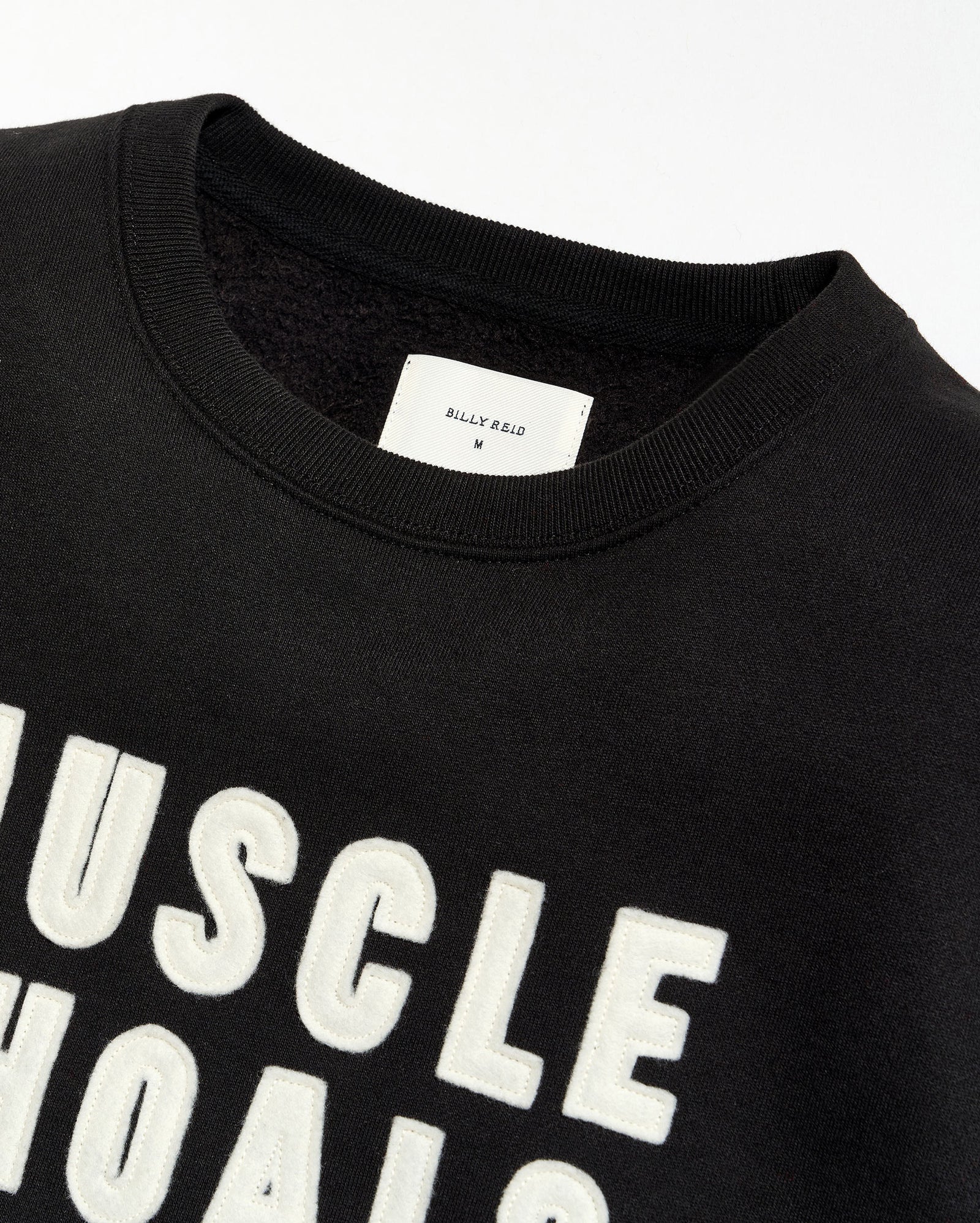 Black t-shirt with 'MUSCLE SHOALS' text and a visible brand label on a white background