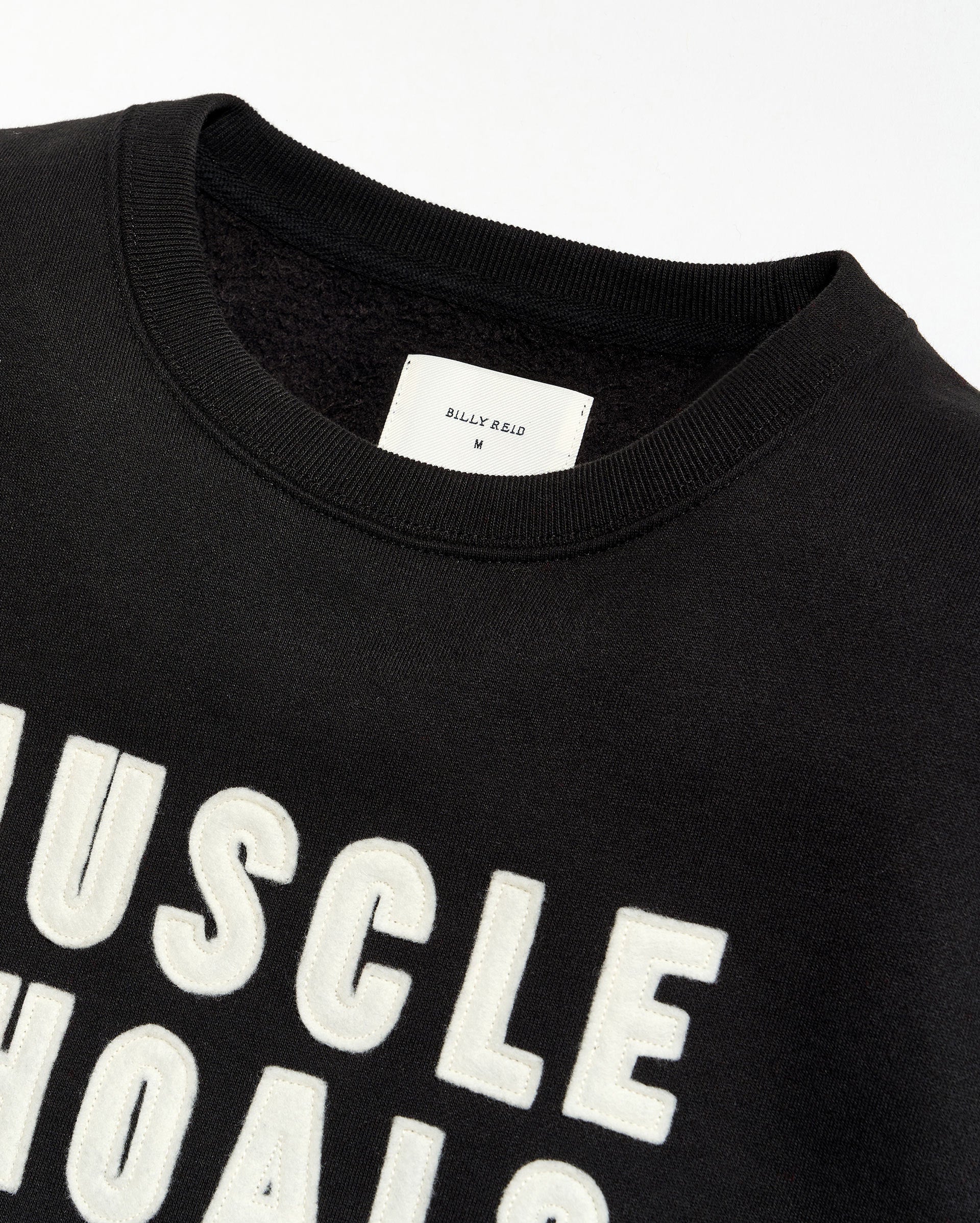 Black t-shirt with 'MUSCLE SHOALS' text and a visible brand label on a white background