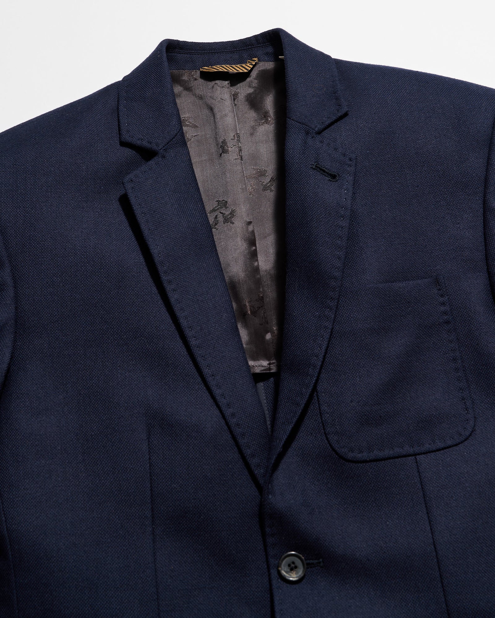 Navy blue blazer with a floral patterned lining on a light gray background