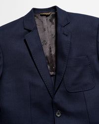 Navy blue blazer with a floral patterned lining on a light gray background