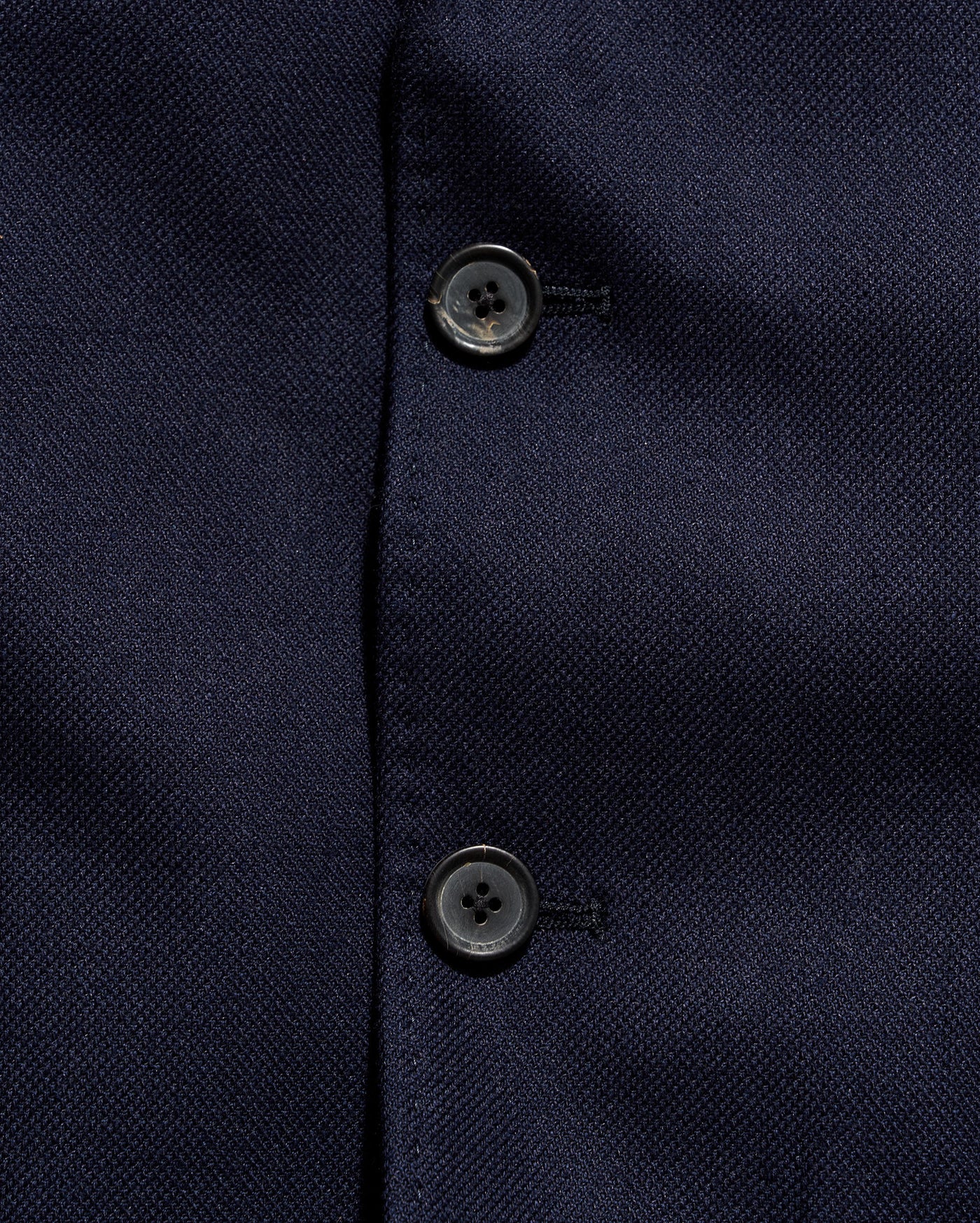 Close-up of a navy blue textured fabric with buttons