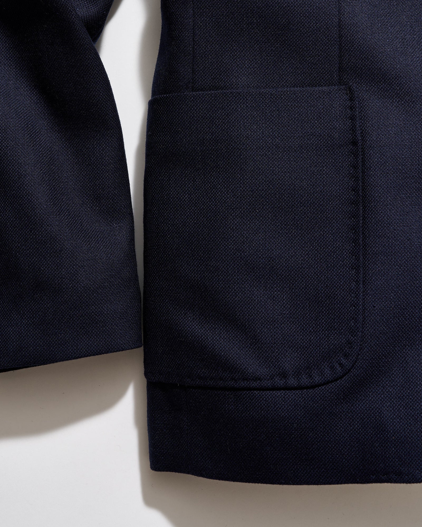 Close-up of a navy blue jacket with a pocket on a light beige background