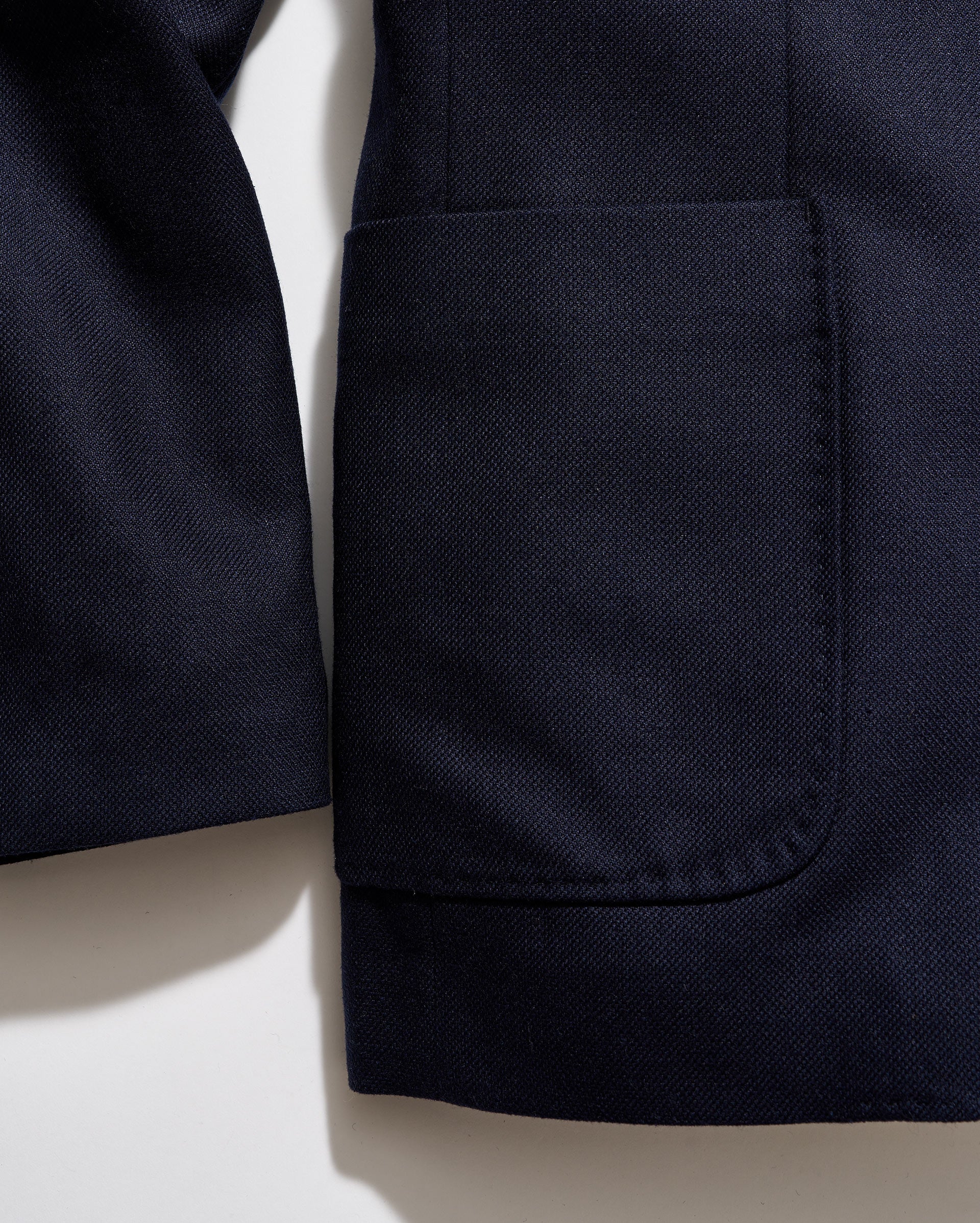 Close-up of a navy blue jacket with a pocket on a light beige background