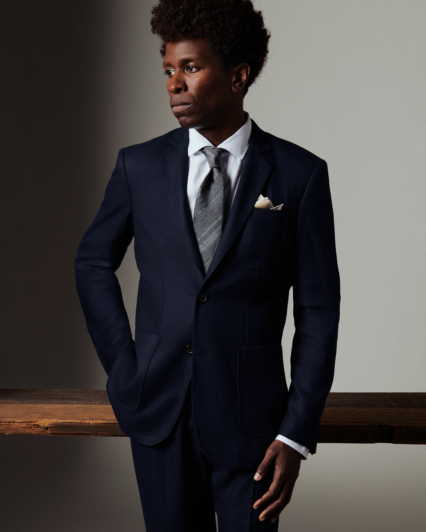 Man wearing a navy suit with a gray tie against a neutral background