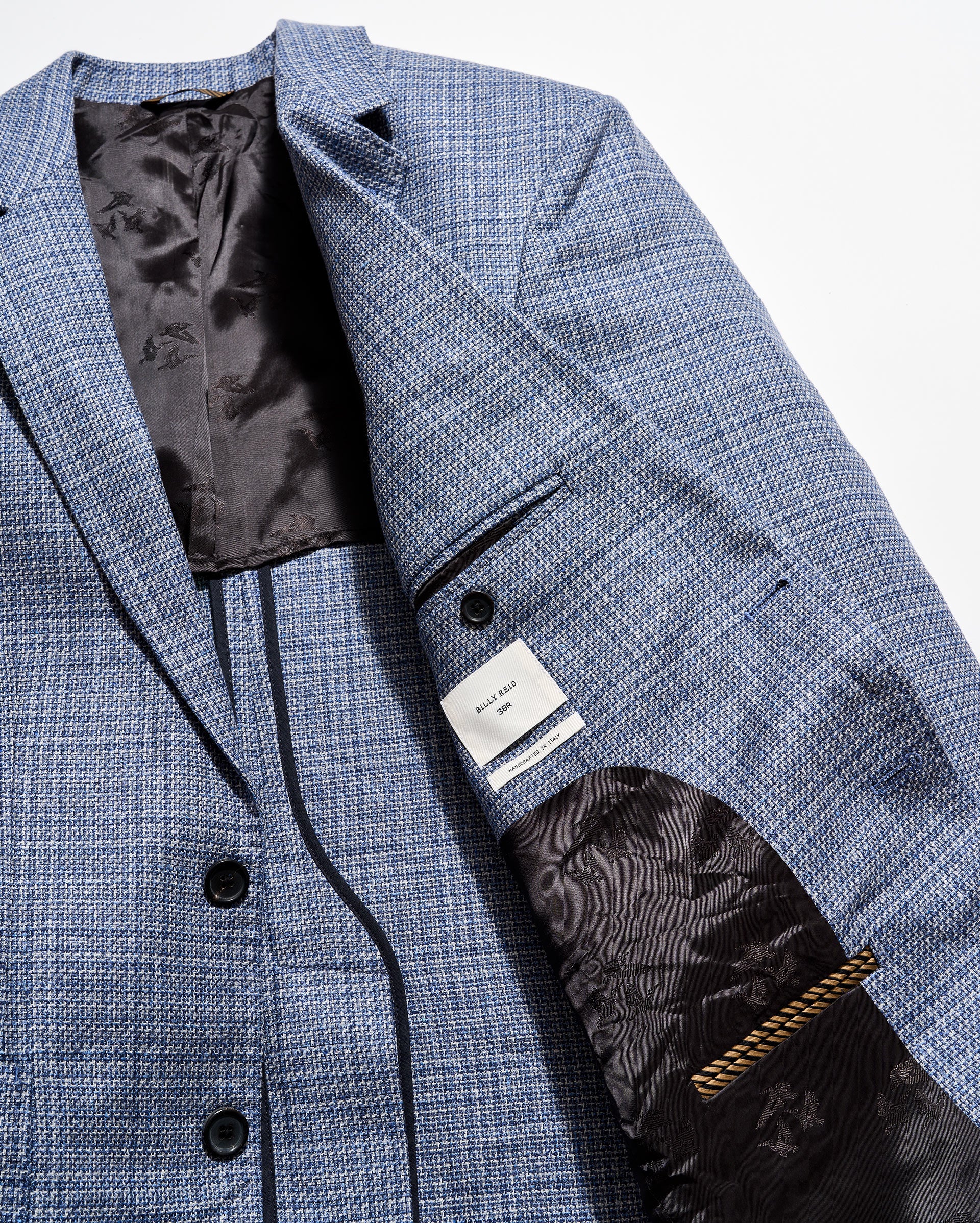 Close-up of a blue checkered suit jacket with a brand label on a white background