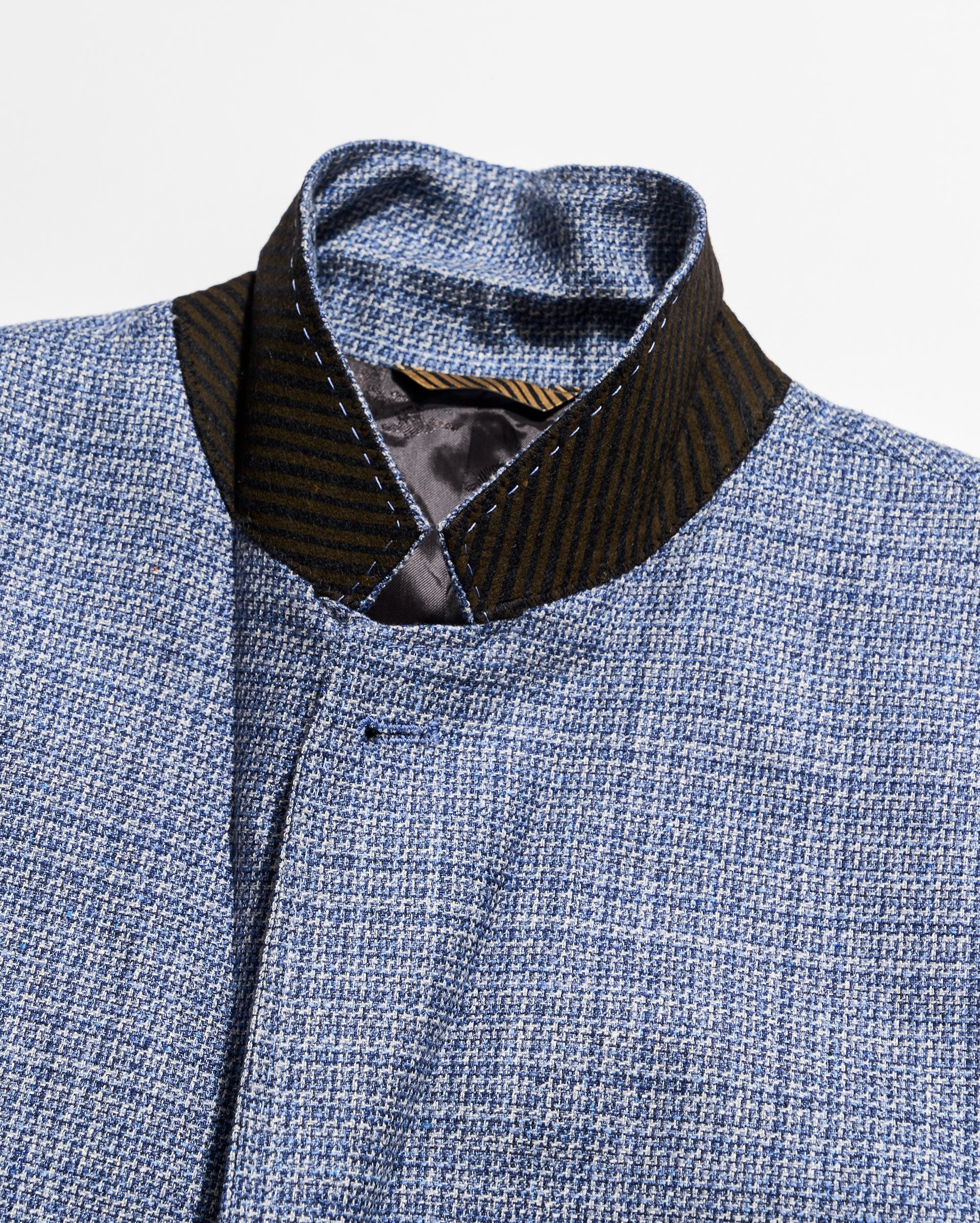 Close-up of a blue textured garment with a black collar and trim.