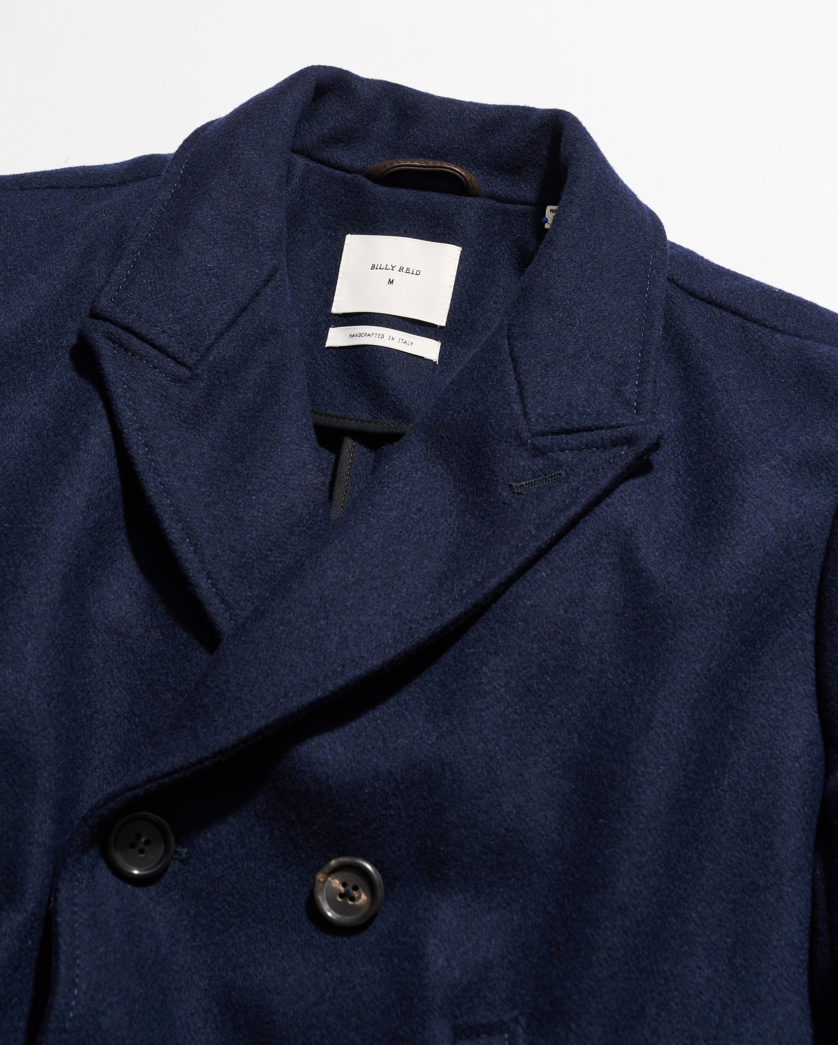 Navy blue coat with a brand label on a white background