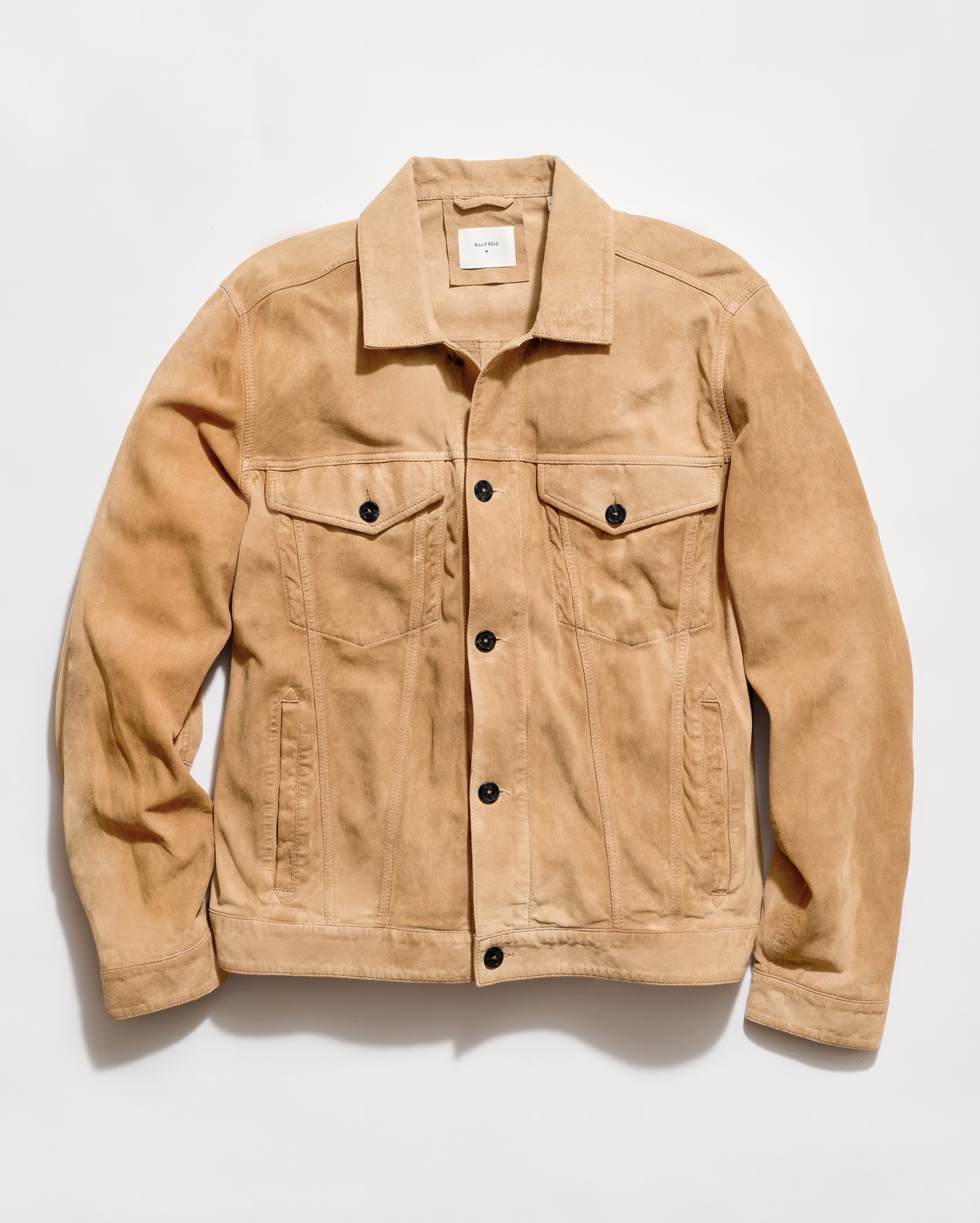 A tan suede trucker jacket with black buttons, laid flat against a light gray background.