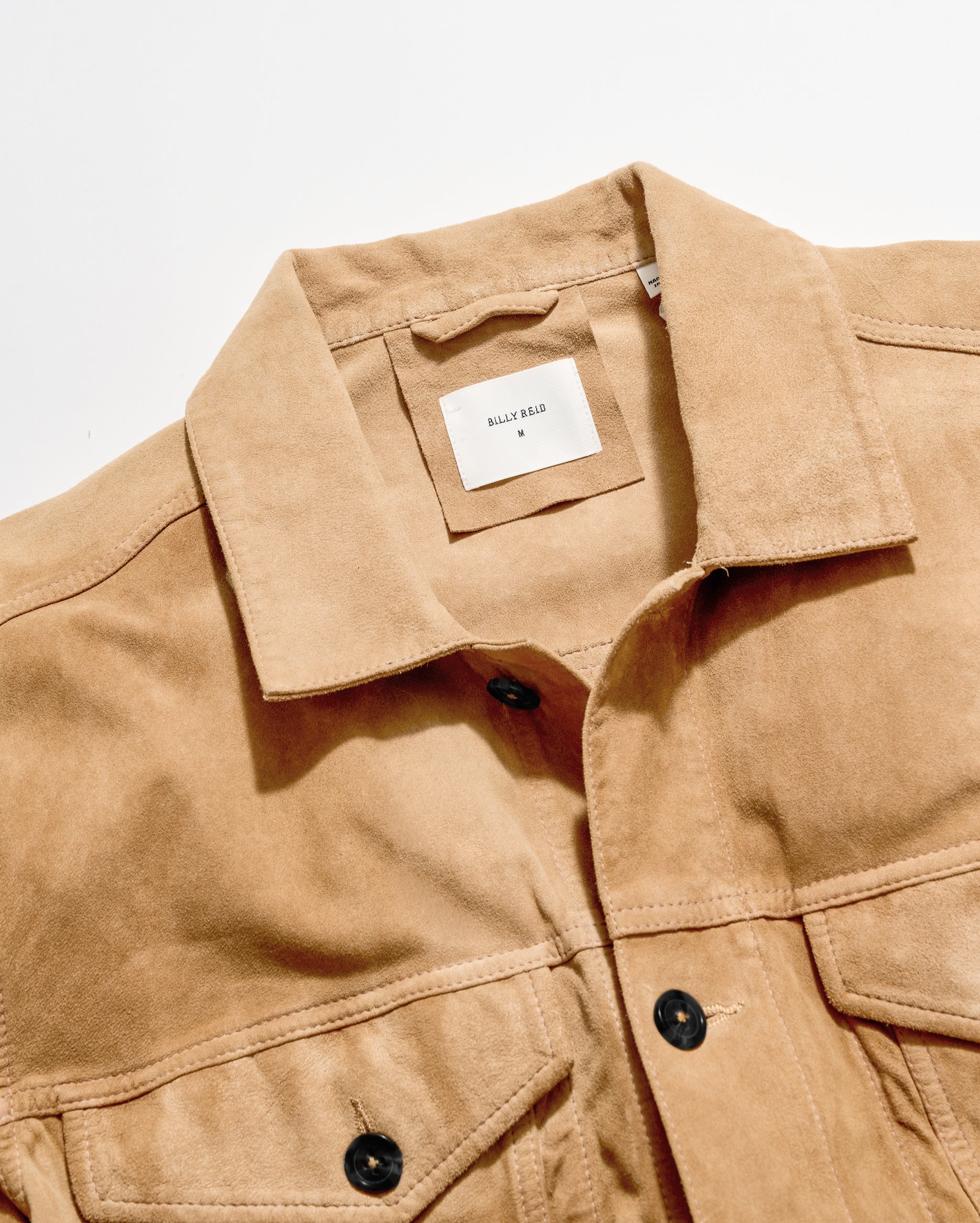 Close-up of a tan suede button-front jacket with a collar and a visible HALF BARE neck label, photographed on a clean white background.