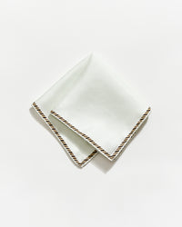 White napkin with gold trim on a white background