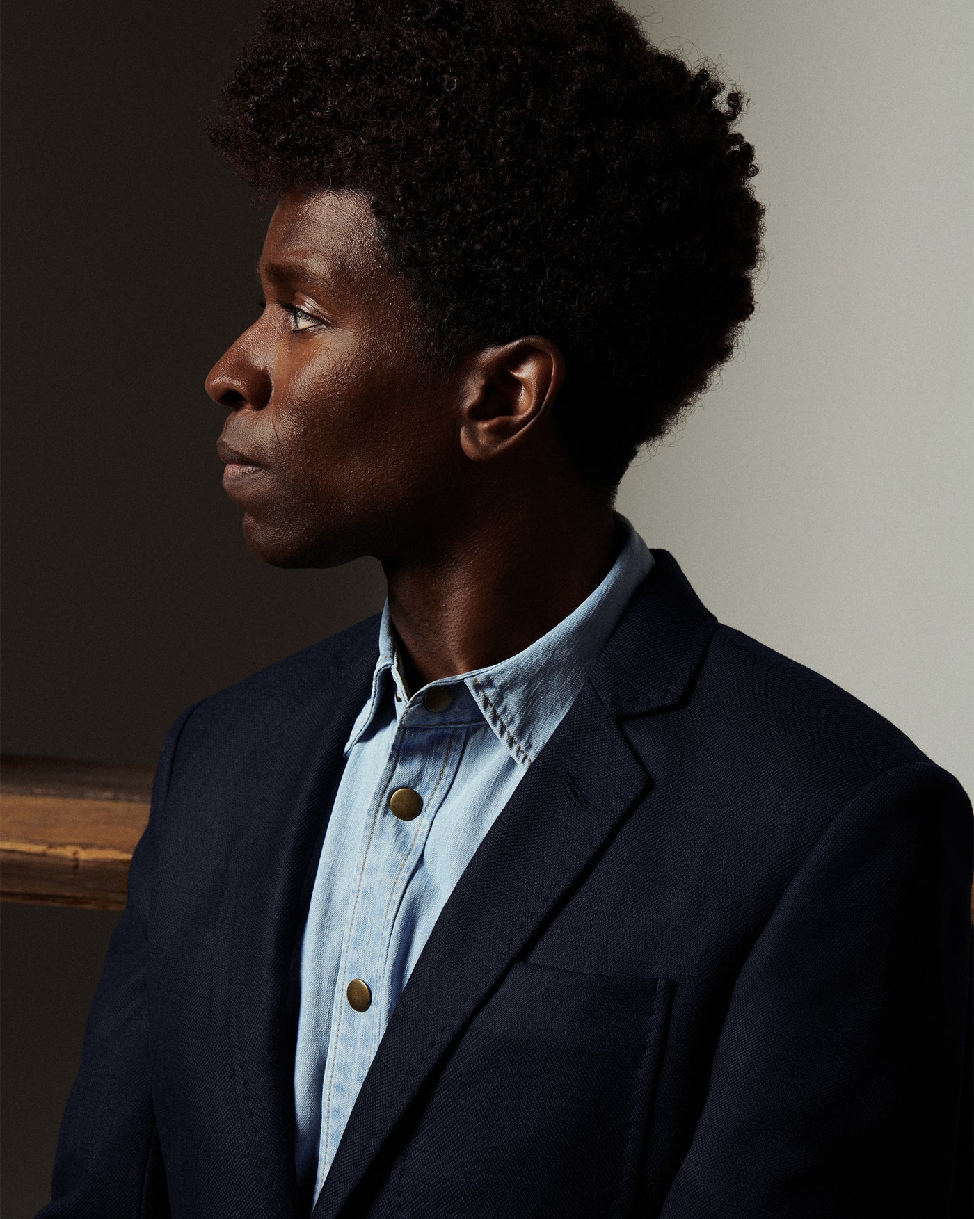 Man wearing a dark blazer over a light blue shirt against a neutral background