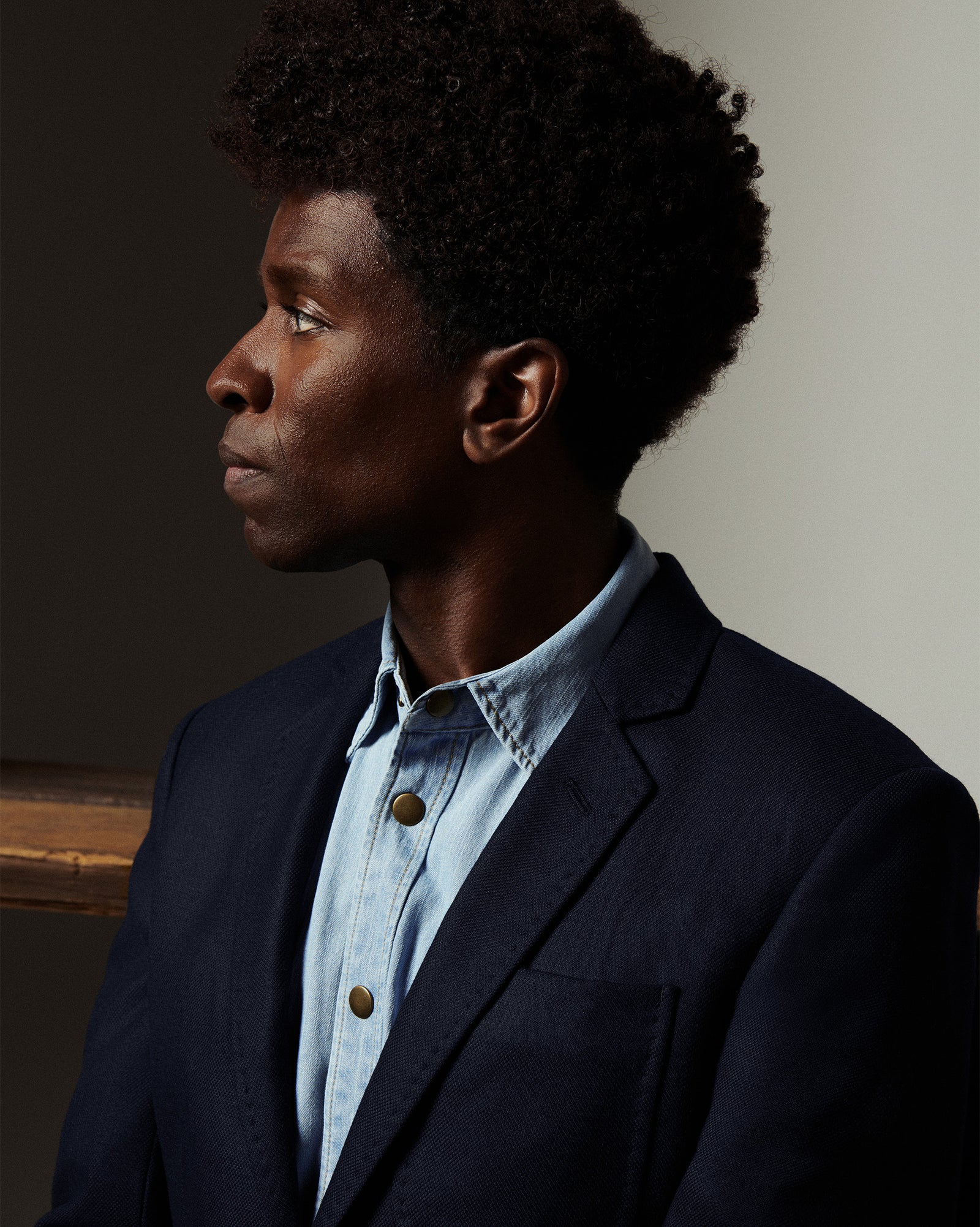 Man wearing a dark blazer over a light blue shirt against a neutral background